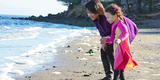 Mother and child at Coyote Point beachfront smiling and looking with wonder at the waves on the sand